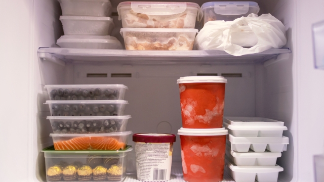 Full of frozen food in refrigerator. Meat, fish, fruit, chocolate, ice and bucket container ice creams flavors on freezer shelves. Stocks of meal and get ready for summer.