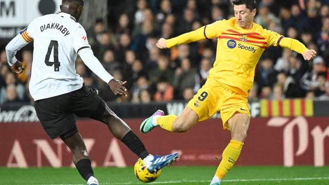 Valencia's Guinean defender #04 Mouctar Diakhaby vies with Barcelona's Polish forward #09 Robert Lewandowski during the Spanish league football match between Valencia CF and FC Barcelona at the Mestalla stadium in Valencia on December 16, 2023. (Photo by JOSE JORDAN / AFP)