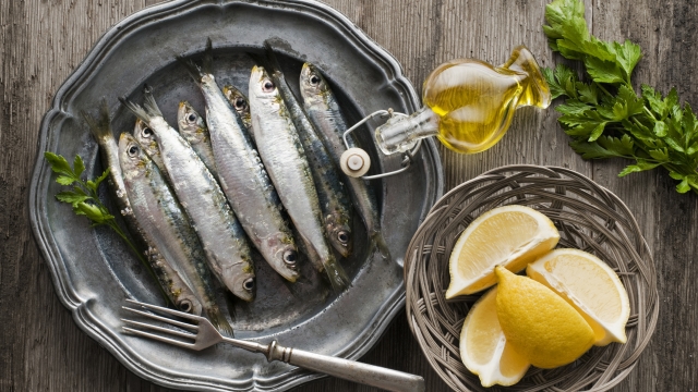 Fresh raw sardines with parsley and lemon on wooden background
