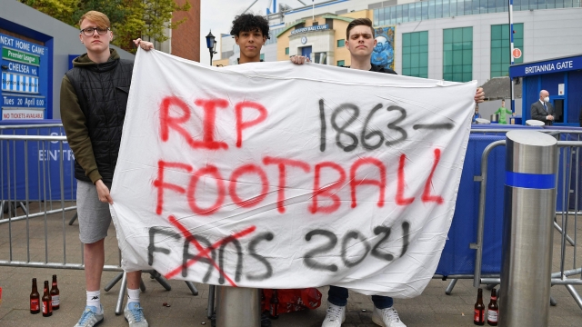 (FILES) A group of supporters hold up a banner critical of the idea of a New European Super League, outside English Premier League club Chelsea's Stamford Bridge stadium in London on April 20, 2021, ahead of their game against Brighton. UK government restates its opposition to Super League after the European Court of Justice ruled UEFA's ban of a Super League involving 12 of the continent's leading clubs broke EU law, Thursday 21, December. (Photo by JUSTIN TALLIS / AFP)
