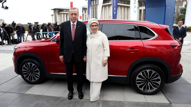 Turkey's President Recep Tayyip Erdogan (L) and his wife Emine Erdogan (R) pose after receiving their Togg T10X, Turkey's first domestically-produced electric car, at the Presidential Complex in Ankara, on April 3, 2023. (Photo by Adem ALTAN / AFP)