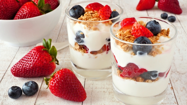 Strawberry and blueberry parfaits in glasses against a bright white wood background