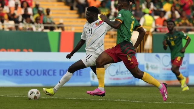 Guinea's Mohamed Bayo, left, shoots the ball to score the opening goal past Cameroon's Christopher Wooh during the African Cup of Nations Group C soccer match between Cameroon and Guinea at the Charles Konan Banny stadium in Yamoussoukro, Ivory Coast, Monday, Jan. 15, 2024. (AP Photo/Sunday Alamba)