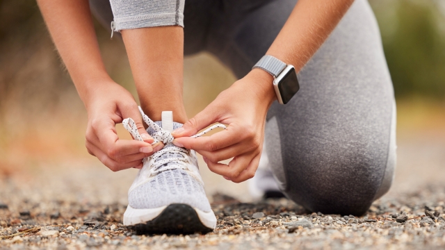Shoes, fitness and exercise with a sports woman tying her laces before training, running or a workout. Hands, health and cardio with a female runner or athlete getting ready for an endurance run