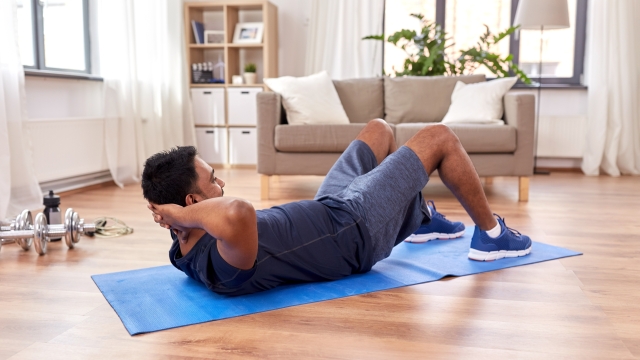 sport, fitness and healthy lifestyle concept - indian man making abdominal exercises at home