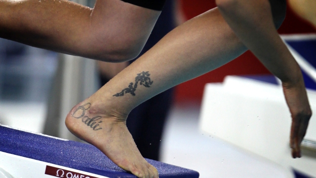 Italian swimmer Federica Pellegrini's tattoos are pictured as she dives to compete in the women's 200m freestyle heats at the 10th FINA World Short Course Swimming Championships in Dubai on December 19, 2010.  AFP PHOTO/PATRICK BAZ (Photo credit should read PATRICK BAZ/AFP via Getty Images)
