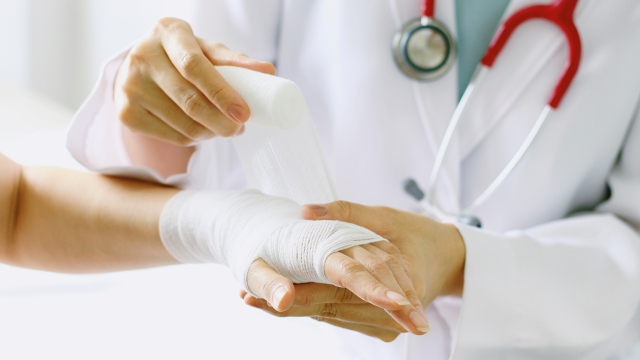 Close-up of female doctor with stethoscope bandaging hand of patient. (Selective Focus)