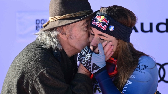 Ezio Goggia (L) kisses his daughter Italy's Sofia Goggia, third, during the podium ceremony of the Women's Downhill event of FIS Alpine Skiing World Cup in Cortina d'Ampezzo, Italy on January 27, 2024. (Photo by Tiziana FABI / AFP)