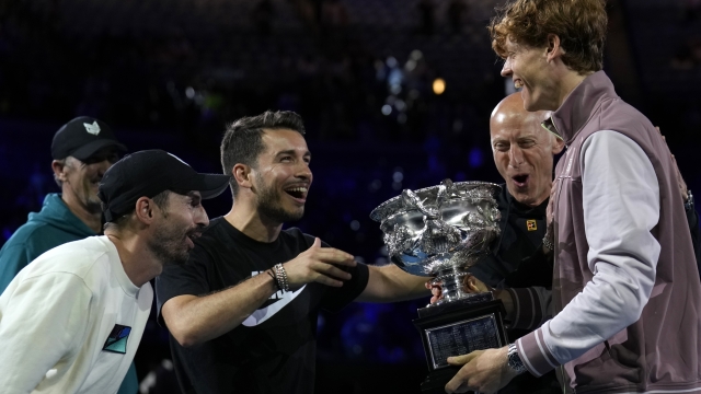 Jannik Sinner, right, of Italy is congratulated by his support team after receiving the Norman Brookes Challenge Cup after defeating Daniil Medvedev of Russia in the men's singles final at the Australian Open tennis championships at Melbourne Park, in Melbourne, Australia, Sunday, Jan. 28, 2024. (AP Photo/Andy Wong)