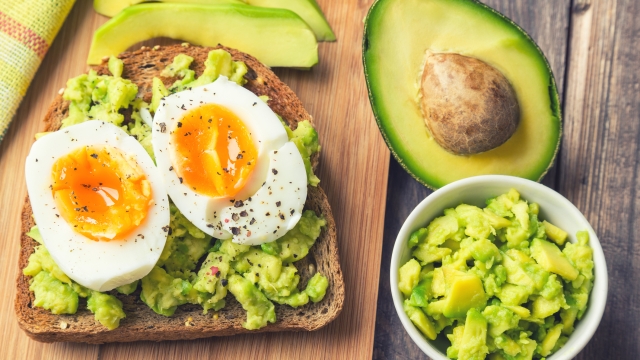 Toast with avocado and egg on rustic wooden background