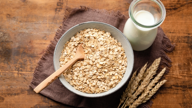 Dry oat flakes, oatmeal, rolled oats and bottle of oat milk on a wooden background. Healthy vegan, vegetarian food. Clean eating, dieting, weight loss concept