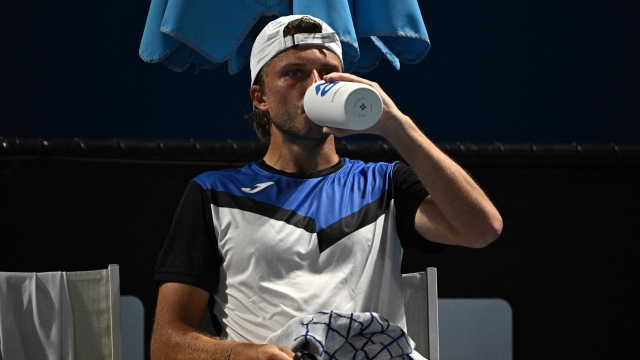 France's Alexandre Muller drinks during a break in his men's singles match against France's Hugo Grenier on day two of the Australian Open tennis tournament in Melbourne on January 15, 2024. (Photo by Anthony WALLACE / AFP) / -- IMAGE RESTRICTED TO EDITORIAL USE - STRICTLY NO COMMERCIAL USE --