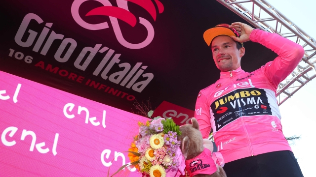 New overall leader Jumbo-Visma's Slovenian rider Primoz Roglic celebrates his overall leader's pink jersey on the podium after winning the twentieth stage of the Giro d'Italia 2023 cycling race, a 18.6 km individual time trial between Tarvisio and Monte Lussari on May 27, 2023. (Photo by Luca Bettini / AFP)