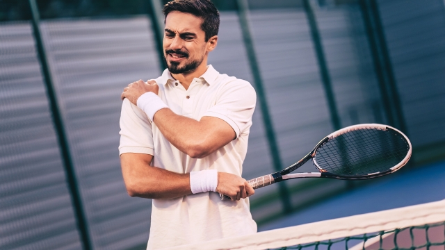 Handsome man on tennis court. Young tennis player. Shoulder pain