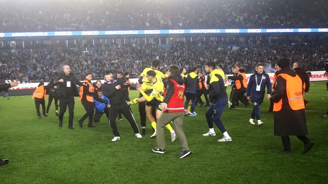 This handout photograph taken and released on March 17, 2024 in Trabzon by Turkish news agency DHA (Demiroren News Agency) shows Fenerbahce's players being attacked by Trabzonspor supporters during the Turkey Super Lig football match between Trabzonspor and Fenerbahce at the Papara Park. (Photo by Handout / DHA (Demiroren News Agency) / AFP) / RESTRICTED TO EDITORIAL USE - MANDATORY CREDIT "AFP PHOTO / DHA (DEMIROREN NEWS AGENCY)" - NO MARKETING NO ADVERTISING CAMPAIGNS - DISTRIBUTED AS A SERVICE TO CLIENTS