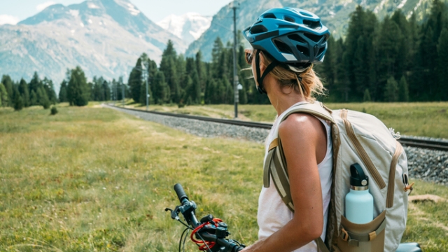 Woman on mountain bike looking at panorama. People enjoying outdoor activities in summer. Girl mountain biker looking at glacier and mountains