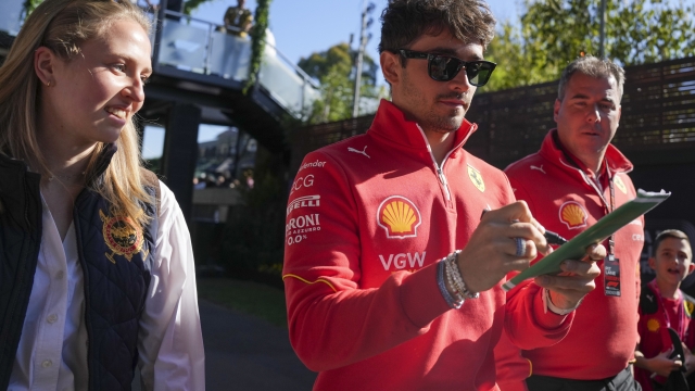 Ferrari driver Charles Leclerc of Monaco signs an autograph as walks into the track ahead of the first practice session of the Australian Formula One Grand Prix at Albert Park, in Melbourne, Australia, Friday, March 22, 2024. (AP Photo/Asanka Brendon Ratnayake)