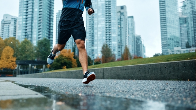 Below view of unrecognizable athlete jogging in the rain. Copy space.