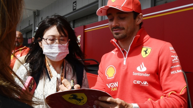 Ferrari's Monegasque driver Charles Leclerc (R) signs an autograph to a fan in the paddock  preparing for the April 7 Formula One Japanese Grand Prix race at the Suzuka circuit in Suzuka, Mie prefecture on April 4, 2024. (Photo by Toshifumi KITAMURA / AFP)