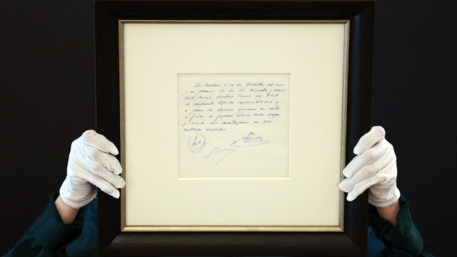 epa11326493 Bonham's auction house staff holds up the Lionel Messi napkin 'contract' for auction at Bonham's in London, Britain, 08 May 2024. The napkin used as a contract or first promise by his father to secure the 13 year old Lionel Messi for Barcelona, is under auction 08-17 May. The napkin and subsequent contract changed the fortunes of Messi, who went on to become one of the greatest soccer players of all time. The napkin is expected to fetch in the region of 300,000 British pounds (around 350,000 euro) .  EPA/ANDY RAIN