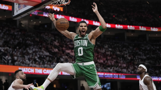 Boston Celtics forward Jayson Tatum (0) dunks between Cleveland Cavaliers guard Max Strus, left, and guard Caris LeVert during the second half of Game 3 of an NBA basketball second-round playoff series Saturday, May 11, 2024, in Cleveland. (AP Photo/Sue Ogrocki)