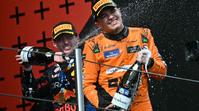 Second-placed McLaren's British driver Lando Norris (R) and race winner Red Bull Racing's Dutch driver Max Verstappen spray champagne on the podium of the Emilia Romagna Formula One Grand Prix at the Autodromo Enzo e Dino Ferrari race track in Imola on May 18, 2024. (Photo by ANDREJ ISAKOVIC / AFP)