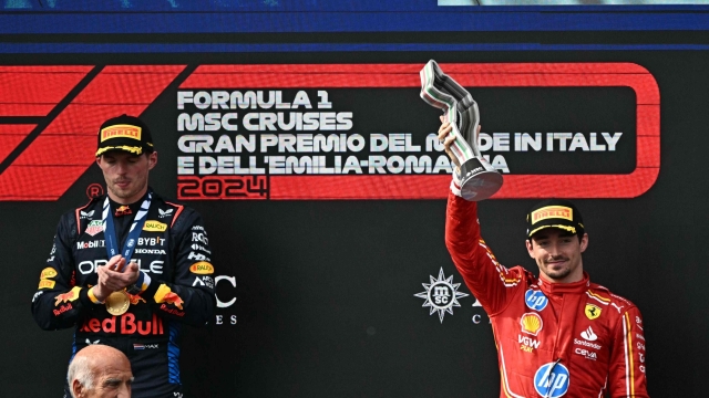 Race winner Red Bull Racing's Dutch driver Max Verstappen (R) applauds as third-placed Ferrari's Monegasque driver Charles Leclerc raises his trophy on the podium of the Emilia Romagna Formula One Grand Prix at the Autodromo Enzo e Dino Ferrari race track in Imola on May 18, 2024. (Photo by GABRIEL BOUYS / AFP)