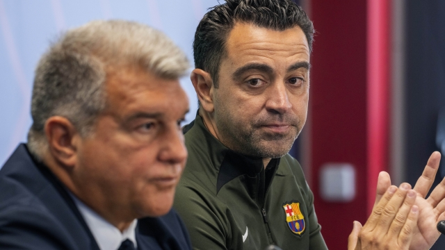 Barcelona's head coach Xavi Hernandez applauds next to Barcelona's president Joan Laporta during a press conference in Barcelona, Spain, Thursday, April 25, 2024. Coach Xavi Hernández will stay with Barcelona for another year after all. He has agreed with the club to finish his contract to 2025 after having decided to quit at the end of the season. (AP Photo/Emilio Morenatti)