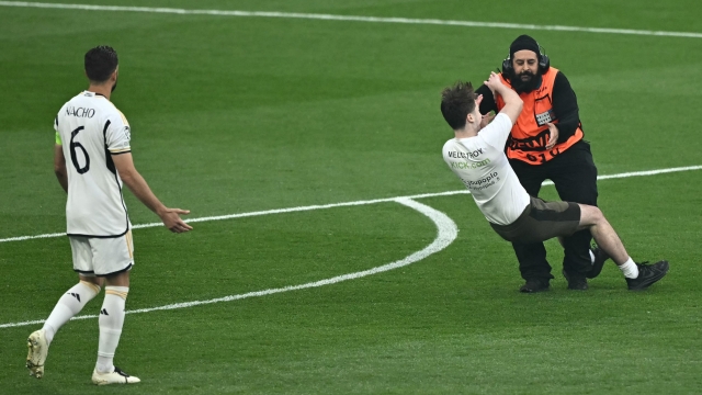 A pitch invader is is tackled by a steward during the UEFA Champions League final football match between Borussia Dortmund and Real Madrid, at Wembley stadium, in London, on June 1, 2024. (Photo by Ben Stansall / AFP)