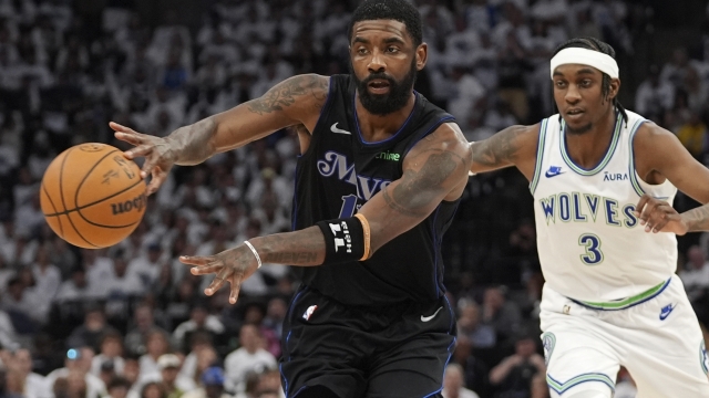 Dallas Mavericks guard Kyrie Irving, left, passes near Minnesota Timberwolves forward Jaden McDaniels (3) during the first half of Game 2 of the NBA basketball Western Conference finals, Friday, May 24, 2024, in Minneapolis. (AP Photo/Abbie Parr)