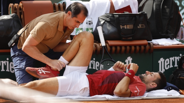 FILE - Serbia's Novak Djokovic receives medical assistance for his right knee during his fourth round match of the French Open tennis tournament against Argentina's Francisco Cerundolo at the Roland Garros stadium in Paris, Monday, June 3, 2024. Novak Djokovic withdrew from the French Open with an injured right knee on Tuesday, June 4, 2024, ending his title defense and meaning he will relinquish the No. 1 ranking. (AP Photo/Jean-Francois Badias, File)