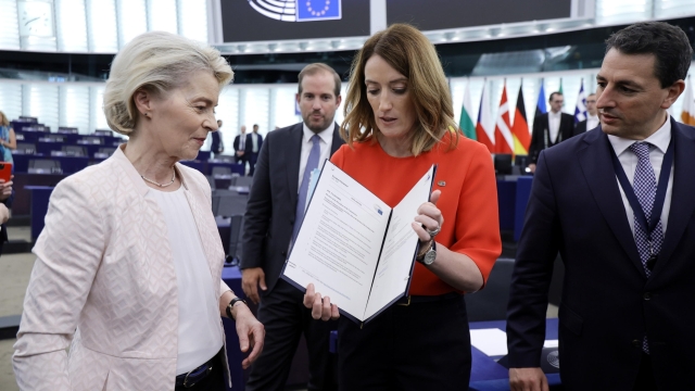 epa11485449 European Parliament President Roberta Metsola (C) shows the appointment documents to Ursula von der Leyen (L) after being re-elected as European Commission President during a plenary session of the European Parliament in Strasbourg, France, 18 July 2024. MEPs re-elected Von der Leyen as European Commission President for the next five years.  EPA/RONALD WITTEK