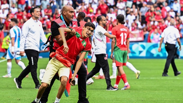 A member of security holds a fan of Morocco after numerous Morocco's fans invaded the pitch at the end of the men's group B football match between Argentina and Morocco during the Paris 2024 Olympic Games at the Geoffroy-Guichard Stadium in Saint-Etienne on July 24, 2024. (Photo by Arnaud FINISTRE / AFP)