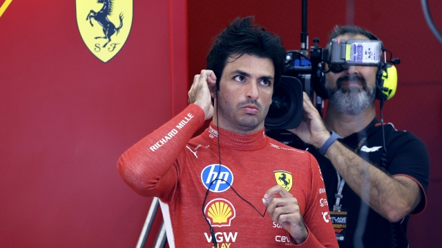 Ferrari driver Carlos Sainz of Spain, left, adjusts his earpiece his team garage prior to the second practice session ahead of the Formula One Grand Prix at the Spa-Francorchamps racetrack in Spa, Belgium, Friday, July 26, 2024. The Belgian Formula One Grand Prix will take place on Sunday. (AP Photo/Geert Vanden Wijngaert)