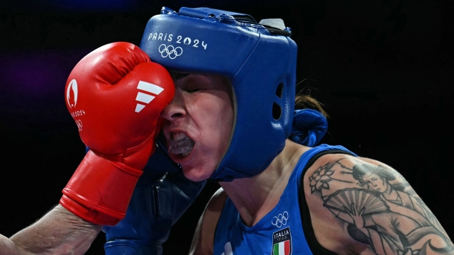 Italy's Irma Testa (in blue) takes a punch from China's Zichun Xu in the women's 57kg preliminaries round of 32 boxing match during the Paris 2024 Olympic Games at the North Paris Arena, in Villepinte on July 30, 2024. (Photo by MOHD RASFAN / AFP)