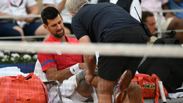 Serbia's Novak Djokovic receives medical treatment for an injury while playing Greece's Stefanos Tsitsipas during their men's singles quarter-final tennis match on Court Philippe-Chatrier at the Roland-Garros Stadium during the Paris 2024 Olympic Games, in Paris on August 1, 2024. (Photo by Patricia DE MELO MOREIRA / AFP)