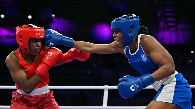 Refugee Olympic Team's Cindy Winner Djankeu Ngamba and France's Davina Michel (Blue) compete in the women's 75kg quarter-final boxing match during the Paris 2024 Olympic Games at the North Paris Arena, in Villepinte on August 4, 2024. (Photo by MOHD RASFAN / AFP)