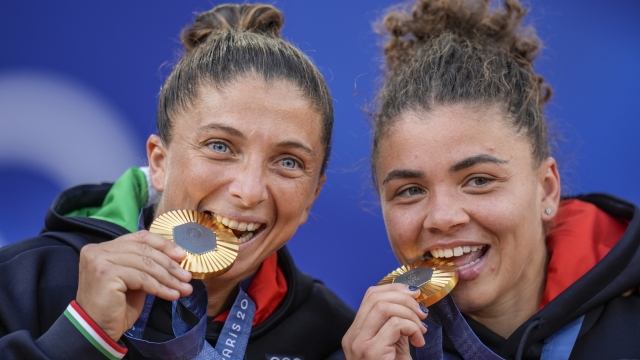 Sara Errani, left, and Jasmine Paolini of Italy show their gold medals after defeating Mirra Andreeva and Diana Shnaider of Individual Neutral Athlete during women's doubles gold medal tennis match at the Roland Garros stadium, at the 2024 Summer Olympics, Sunday, Aug. 4, 2024, in Paris, France. (AP Photo/Manu Fernandez)