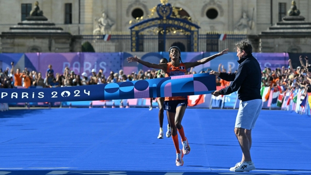 Netherlands' gold medallist Sifan Hassan crosses the finish in first place followed by Ethiopia's silver medallist Tigst Assefa in the women's marathon of the athletics event at the Paris 2024 Olympic Games at The Invalides in Paris on August 11, 2024. (Photo by Andrej ISAKOVIC / AFP)