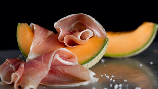 Jambon mix. Ham. Traditional Italian and Spanish salting, smoking, dry-cured dish - jamon Serrano and prosciutto crudo sliced with melon on grey background. Copy space. Closeup.