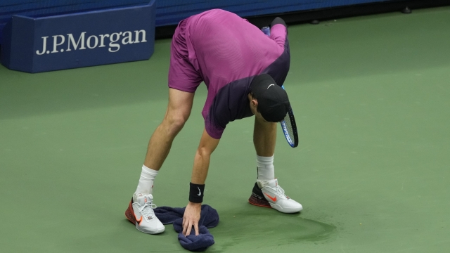 Jack Draper, of Great Britain, wipes the court against Jannik Sinner, of Italy, during the men's singles semifinals of the U.S. Open tennis championships, Friday, Sept. 6, 2024, in New York. (AP Photo/Seth Wenig)