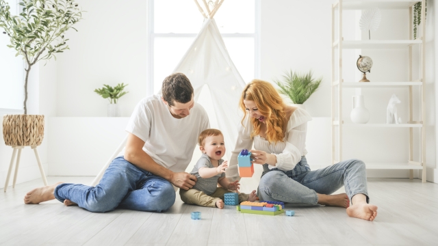 A young mother and father with her little son playing at home with toys