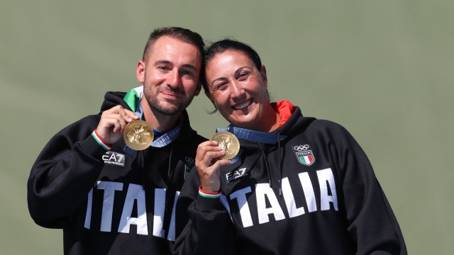 Gold medallists Italy's Diana Bacosi and Italy's Gabriele Rossetti celebrate on the podium during the award ceremony for the Skeet Mixed Team Final during the Paris 2024 Olympic Games at Chateauroux Shooting Centre on August 5, 2024. (Photo by ALAIN JOCARD / AFP)