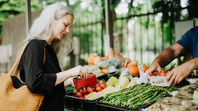 Portrait of a beautiful mature woman shopping at market in the city. Middle-aged woman buying fresh vegetables and fruits from market stall.