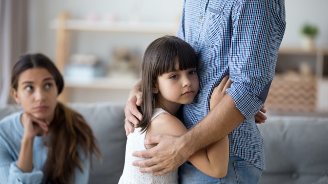 Sad little girl hug father upset by father leaving on business trip, unhappy young family in living room with preschooler daughter embrace say goodbye to father, parents divorce hurt small child