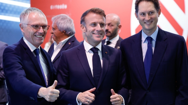 epa11658659 French President Emmanuel Macron (C) poses alongside Stellantis CEO Carlos Tavares (L) and Stellantis chairperson John Elkann (R) during his visit to the Stellantis stand at the Paris Motor Show in Paris Expo Porte de Versailles in Paris, France, 14 October 2024. The 90th edition of the biennial Paris Motor Show runs from 14 to 20 October 2024.  EPA/LUDOVIC MARIN / POOL  MAXPPP OUT