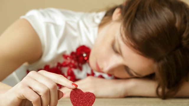 Sad lonely woman holding red heart.  Being alone on Valentine's day. Heartbreak, divorce or breakup concept.