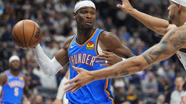 Oklahoma City Thunder guard Shai Gilgeous-Alexander, left, looks to pass the ball as Denver Nuggets forward Michael Porter Jr. defends in the second half of an NBA basketball game Thursday, Oct. 24, 2024, in Denver. (AP Photo/David Zalubowski)