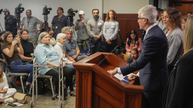 Los Angeles County District Attorney George Gascon, right, flanked by Menedez family members talks during a news conference at the Hall of Justice on Thursday, Oct. 24, 2024, in Los Angeles. (AP Photo/Damian Dovarganes)