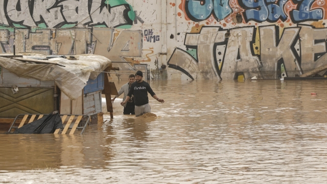 epa11691924 People walk through a flooded area next to the V-30 highway, which was submerged by significant rainfall in the city of Valencia, eastern Spain, on 30 October 2024. The State Meteorological Agency (AEMET) has issued red alerts for rainfall in multiple regions of the province of Valencia, caused by the severe storm DANA. The storm has impacted multiple areas of the city, resulting in the loss of at least 13 lives due to the flooding.  EPA/BIEL ALINO